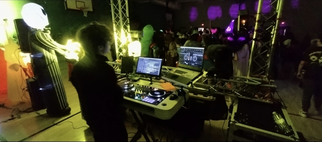 DJ Aiden Jules performing at a themed community event with a costumed crowd and stage lighting