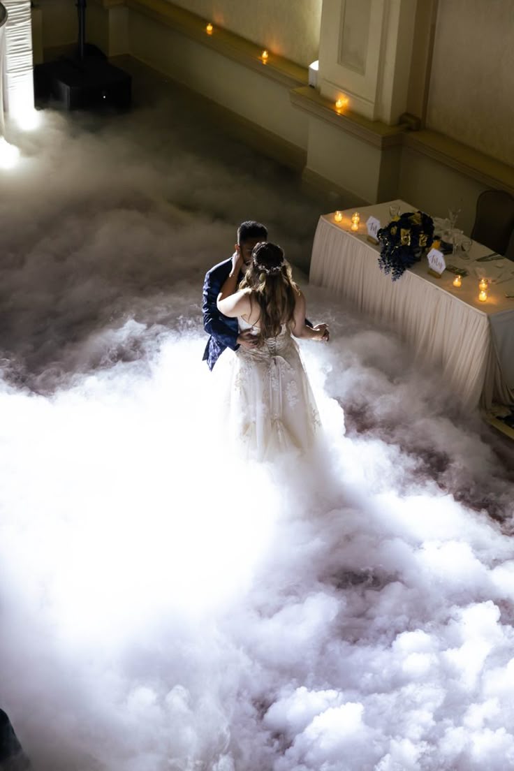 Bride and groom sharing a first dance surrounded by low-lying fog in an elegant ballroom